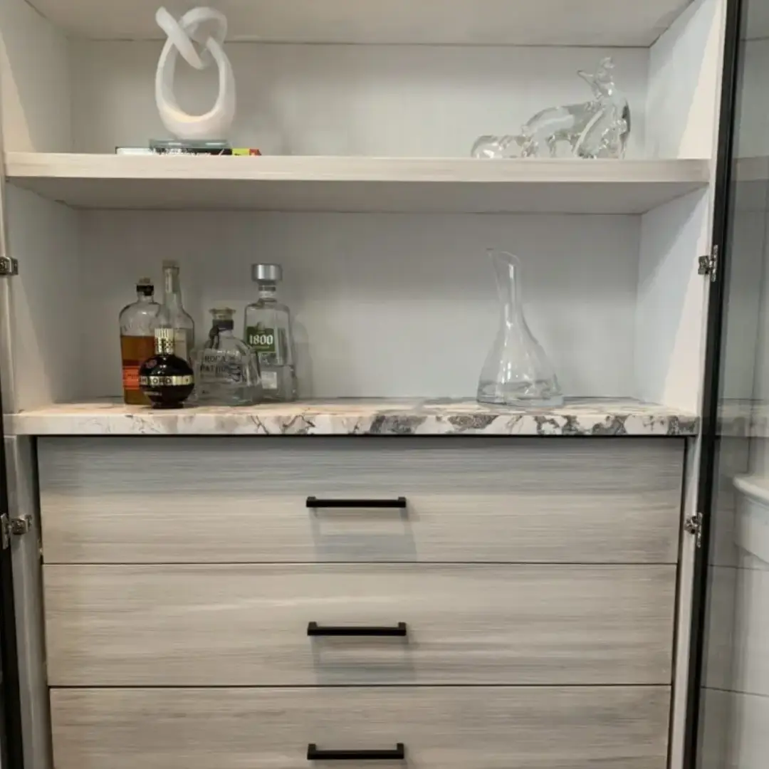 A white cabinet with some bottles and glasses on it
